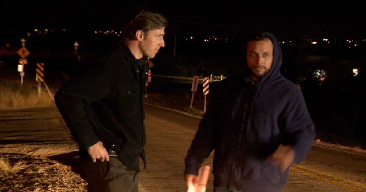 Man being interviewed/detained by police officer, appears to be suspect or person of interest being questioned